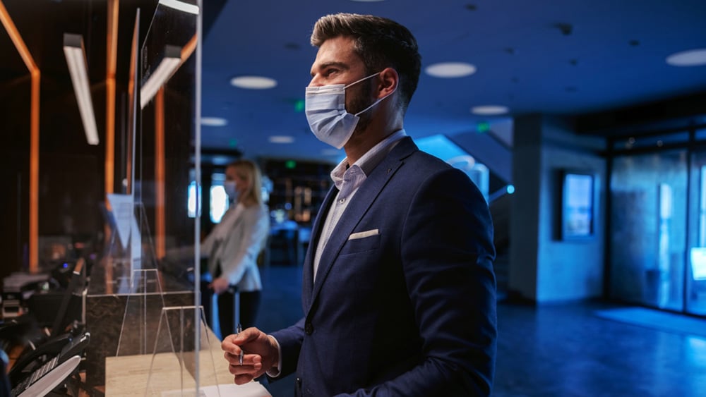 A man wearing a face mask in front of the resort reception A man wearing a face mask in front of the resort reception